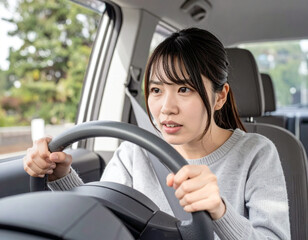 恐る恐る車を運転するペーパードライバーの若い女性