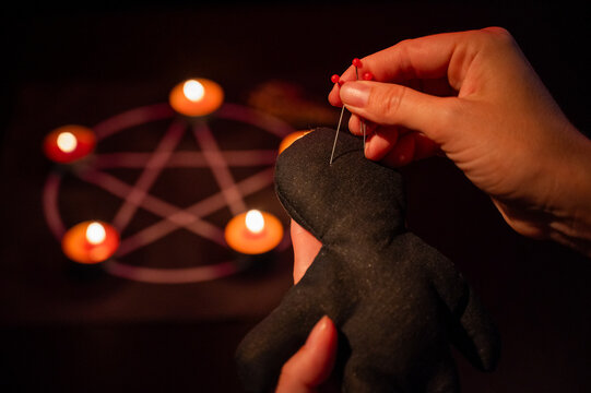 Woman sticking pins into voodoo doll. 