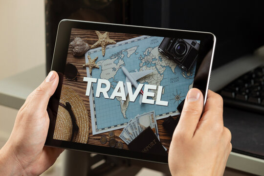 a male hands holding a tablet with the travel word over a travel concept image