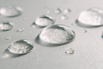 Clear water droplets on smooth glass surface, macro shot showing transparent liquid beads with soft reflections, clean and fresh feeling, close up detail, minimalistic background