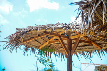 bottom view of a straw umbrella with a wooden frame against a clear sky for advertising space.