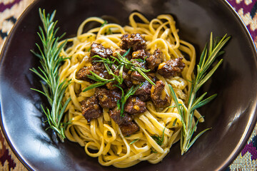 Pasta with braised beef and rosemary garnish