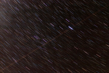 Numerous luminous star trails create a dynamic pattern against the deep expanse of the night sky,...