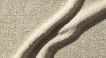 Closeup of a textured beige fabric with two prominent curved folds creating shadow patterns