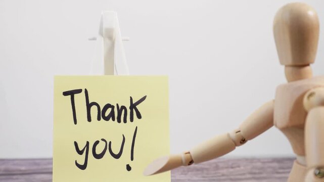 A small pan to a scene of a wooden mannequin displaying the word "thank you!" on a sticky note