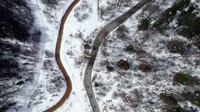 Drone view of snow covered stream, road and hiking path in mountain forest in sunny winter day, autumn landscape in Bipeng valley in Sichuan, China, 4k real time footage, travel concept.