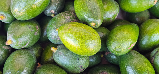 Fresh green avocados stacked on display at a local market in Granada, Spain, showcasing their rich texture and natural shine. fruit market