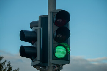 A green traffic light stands tall against a bright blue sky, indicating 'go' for vehicles on the...