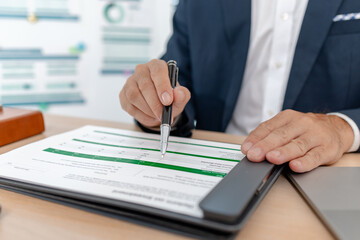 A businessman in a suit analyzing financial charts and performance reports in a bright modern office, focusing on strategy, data, and budget planning for company growth and long-term success.