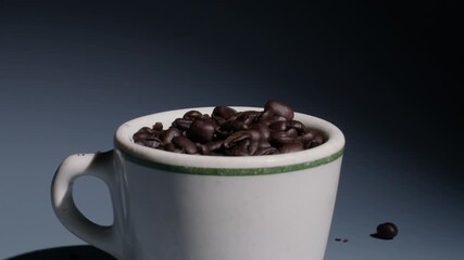 Extreme slow motion, 120fps, close-up of vintage coffee cup with green stripe filled with coffee beans as a few coffee beans fall into cup and bounce out. - Powered by Adobe