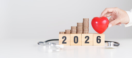 Happy New Year 2026 with doctor Stethoscope, coins stack and red heart on table. health care, Money...