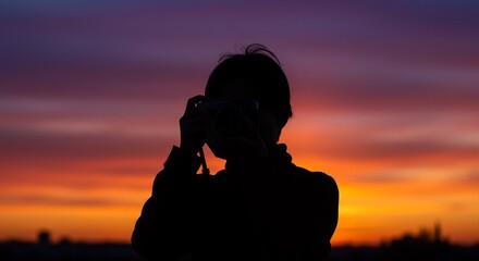 Silhouette of a person taking a photo during sunset.