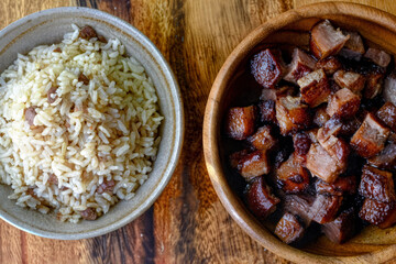 A comforting Asian meal featuring seasoned rice paired with tender, caramelized pork belly cubes, delivering a perfect balance of savory and rich flavors.