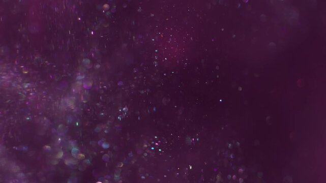 Glitter glow wave. Defocused gleam. Dust stream mix ink haze emulsion. Violet purple sequins color glisten texture abstract blur background.