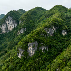 Enshi City Hubei Province hills are covered by dense green vegetation with rocky outcrops providing textural contrast.