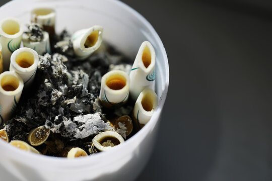 Discarded Cigarette Butts and Ashes in a Container: Environmental Impact and Littering Concerns