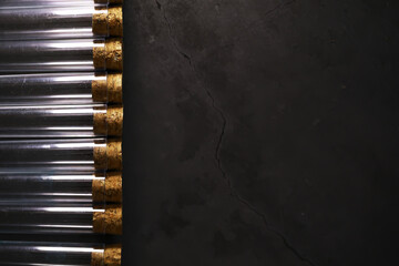 Organized Glass Test Tubes with Cork Stoppers on Dark Textured Surface for Scientific Exploration