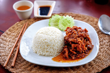 Filipino-style rice topped with savory marinated meat and a tangy sauce, served with a side of fresh cucumber salad.