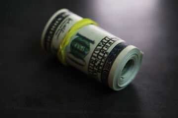 Rolled Hundred Dollar Bill on Dark Surface Reflecting Financial Stability and Wealth Concept