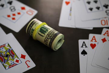 Fototapeta na wymiar Roll of Cash and Playing Cards on Dark Surface Signifying Gambling and Risk