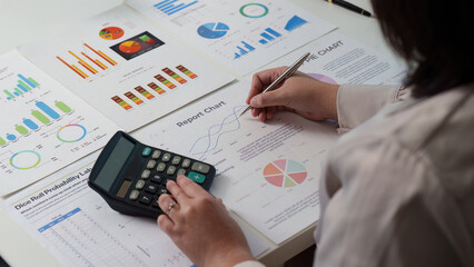 Data Analysis. Professional analyzing charts and graphs with calculator and pen.