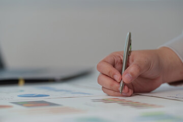 Focused Analysis. Close-up of hand writing on financial reports with pen.