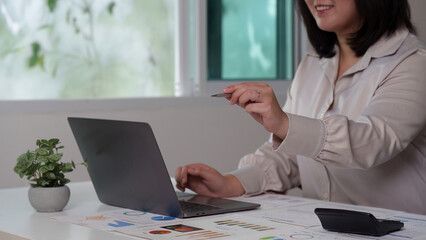 Engaged Analyst. Smiling professional reviewing data on laptop with pen.