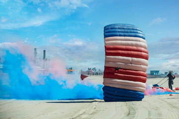 A parachute team lands in the sand marked by colored smoke