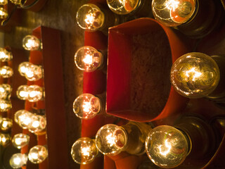 Close-up of letters with surrounding bright light bulbs of a big signage display on dark wall for a retro bar