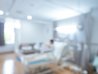 Blurred image of a modern white clean hospital recovery room with patient resting on bed, showing peaceful atmosphere, privacy, and clean medical environment in a healthcare facility.