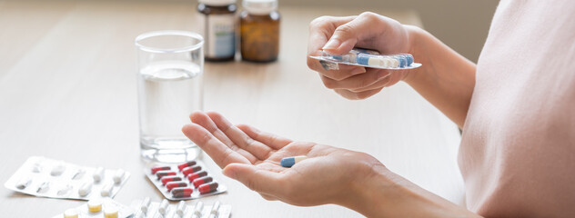 Sick ill asian young woman, girl hand taking tablet pill capsule out from blister pack, painkiller...