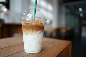 Close up plastic take away cup of iced Latte coffee on wooden table