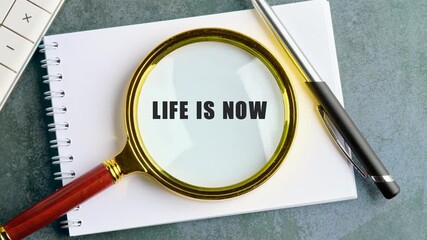 A magnifying glass focuses on the words Life Is Now, highlighting the importance of seizing the present moment for business strategy and achieving success