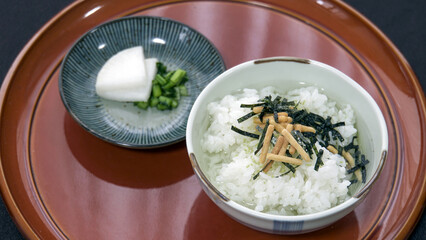 茶色の塗り盆の上に置かれたお茶漬けと大根の漬物のセット