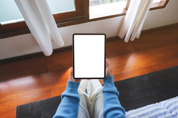 Top view mockup image of a woman holding tablet with blank desktop white screen at home