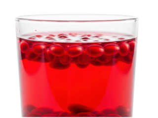 Glass of refreshing red berry juice with whole berries floating on a transparent background