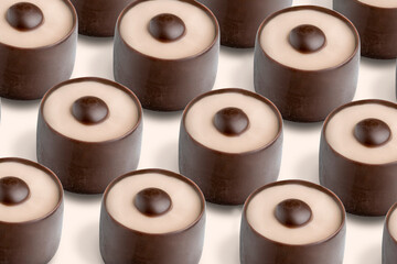 A collection of delightful chocolate candies are neatly placed in a row, each featuring a smooth beige layer with a dark chocolate center. The sweets create an inviting dessert display.