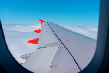 Obraz premium View of an airplane wing above fluffy clouds during a bright daytime flight