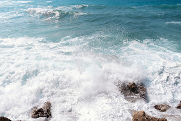 Waves crashing against rocky shore at a sunny beach in daytime