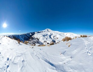 Expansive fisheye view of a snow-covered mountain range under a clear, bright blue sky with a radiant sun. Panoramic landscape