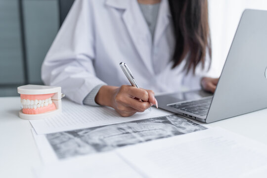 Dentist at dental clinic White healthy tooth with Dental model in oral surgeons discussing jaw x-ray on tablet medicine healthcare oral surgery concept