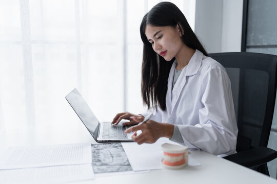 Dentist at dental clinic White healthy tooth with Dental model in oral surgeons discussing jaw x-ray on tablet medicine healthcare oral surgery concept