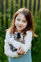 Young girl gently cuddles a fluffy bunny in her arms.