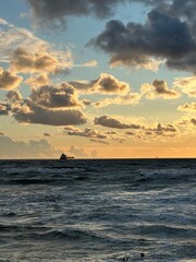 Fototapeta premium Cargo ship on distant horizon at sea during sunset