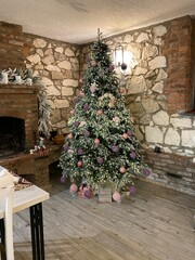 Christmas tree decorated with lights and ornaments in cozy rustic living room interior