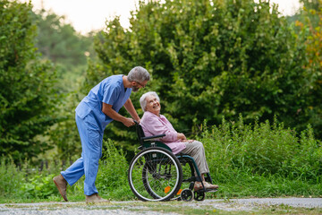 Senior patient and male nurse talking during walk outdoors.