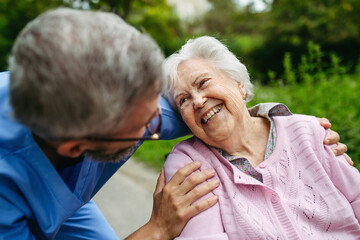 Senior patient and male nurse talking during walk outdoors.