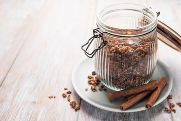 Granola cereal in glass jar with cinnamon sticks