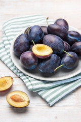 Obraz premium Fresh ripe plums in grey bowl on wood table