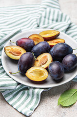 Fresh ripe plums with halves on plate for healthy eating